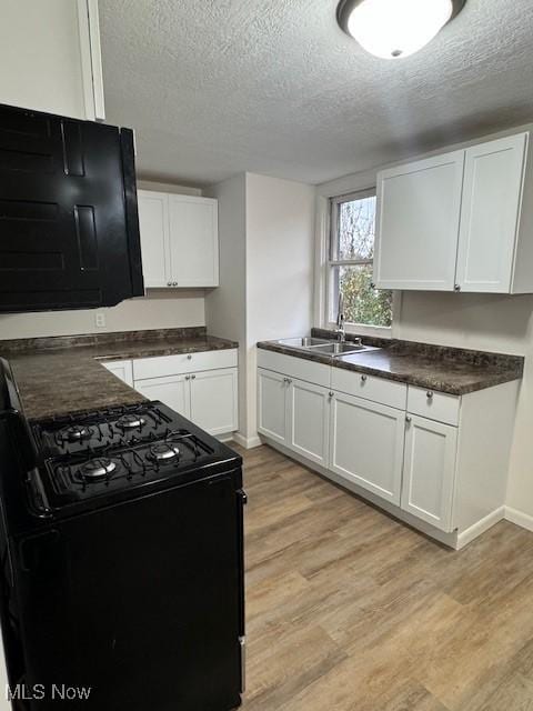 10630 Valley St, Trimble, OH 45782 - kitchen with light hardwood / wood-style floors, a textured ceiling, black range with gas stovetop, white cabinets, and sink