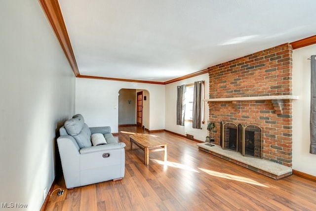 living room with wood-type flooring, a brick fireplace, and crown molding