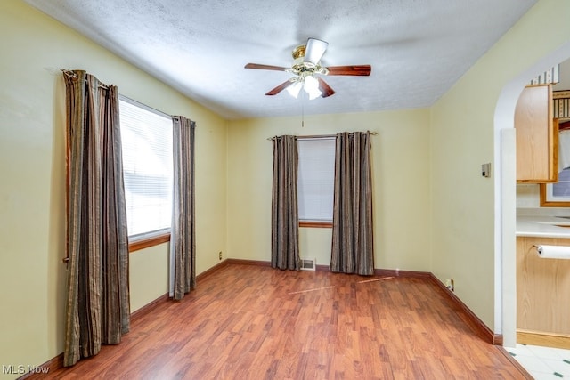 empty room featuring ceiling fan, a textured ceiling, and light hardwood / wood-style floors