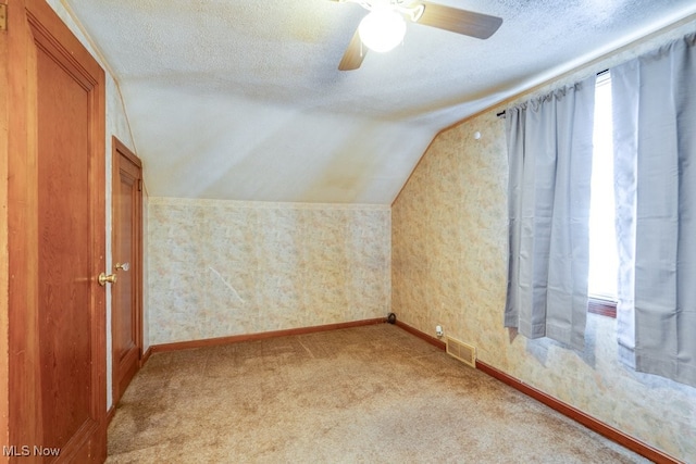 additional living space featuring ceiling fan, light colored carpet, a textured ceiling, and vaulted ceiling