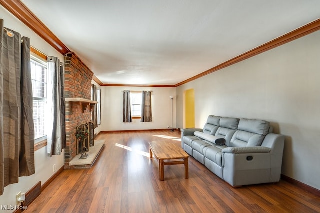 living room featuring a fireplace, wood-type flooring, crown molding, and a healthy amount of sunlight