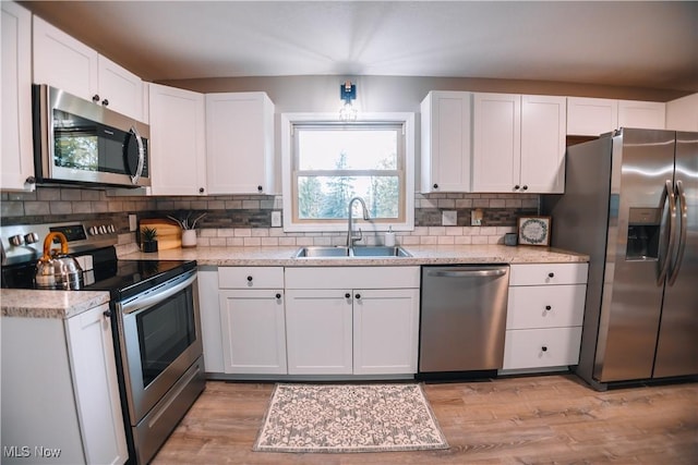 kitchen with white cabinets, sink, stainless steel appliances, and light hardwood / wood-style flooring