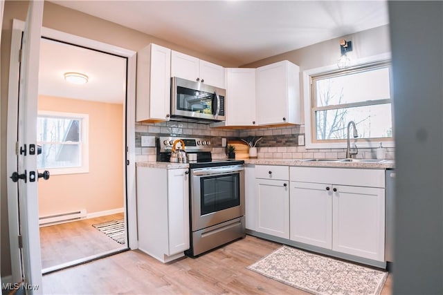 kitchen with white cabinetry, a baseboard heating unit, stainless steel appliances, light hardwood / wood-style floors, and sink