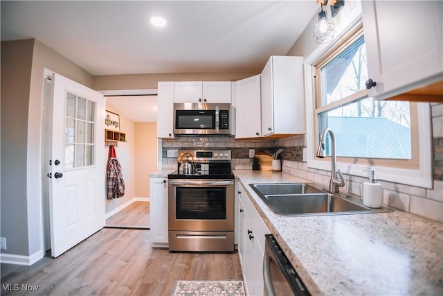 kitchen with appliances with stainless steel finishes, decorative backsplash, white cabinetry, and sink