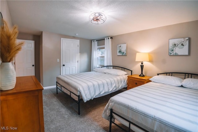 bedroom with a textured ceiling and dark colored carpet