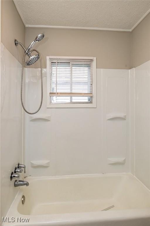 bathroom with a textured ceiling and washtub / shower combination