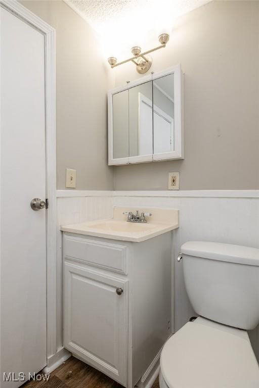 bathroom featuring hardwood / wood-style flooring, a textured ceiling, toilet, and vanity