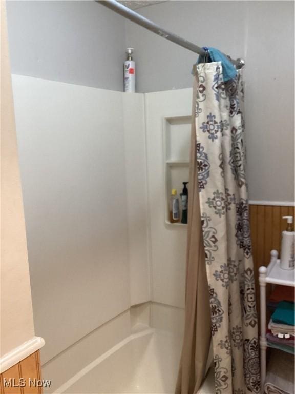 bathroom with shower / tub combo and wood walls