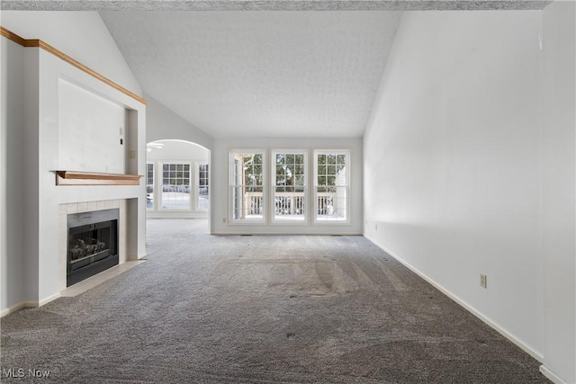 2834 Caxton Cir, Akron, OH 44312 - unfurnished living room with a tiled fireplace, a textured ceiling, arched walkways, carpet flooring, and vaulted ceiling