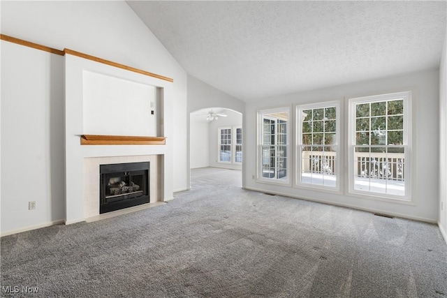 2834 Caxton Cir, Akron, OH 44312 - unfurnished living room with visible vents, a tiled fireplace, a textured ceiling, carpet, and lofted ceiling
