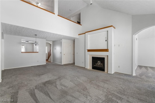 unfurnished living room with high vaulted ceiling and carpet flooring