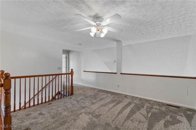 carpeted empty room featuring ceiling fan and a textured ceiling