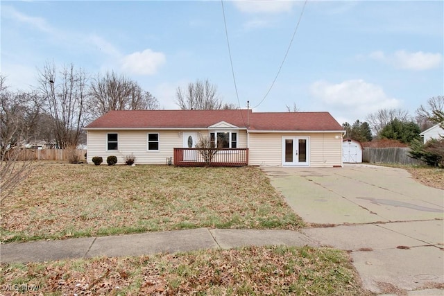 rear view of property featuring french doors, a storage unit, a deck, and a yard