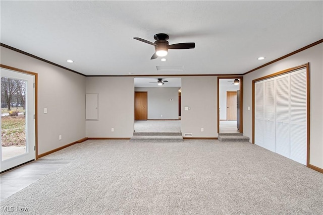 unfurnished living room featuring ceiling fan, light colored carpet, and ornamental molding