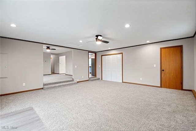 unfurnished living room featuring ceiling fan, ornamental molding, and carpet floors