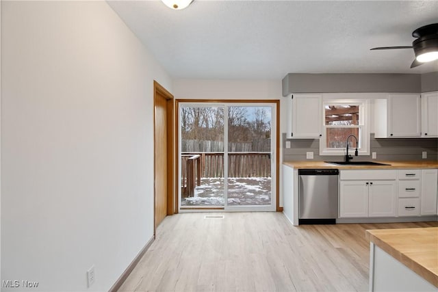 kitchen with white cabinetry, stainless steel dishwasher, light hardwood / wood-style flooring, and sink