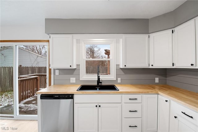 kitchen with stainless steel dishwasher, sink, and white cabinetry