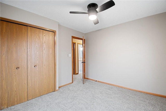 unfurnished bedroom featuring ceiling fan, a closet, and light carpet