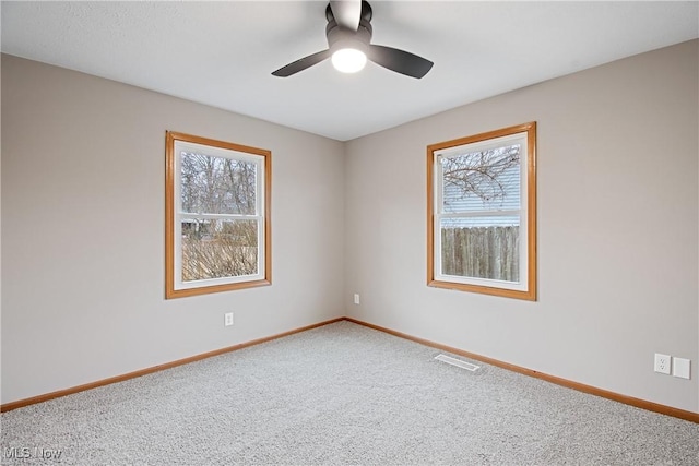 spare room with ceiling fan, a wealth of natural light, and carpet flooring