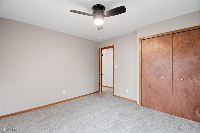 unfurnished bedroom featuring ceiling fan, a closet, and light carpet