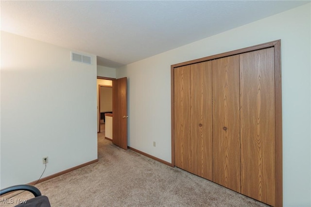 unfurnished bedroom with a closet and light colored carpet