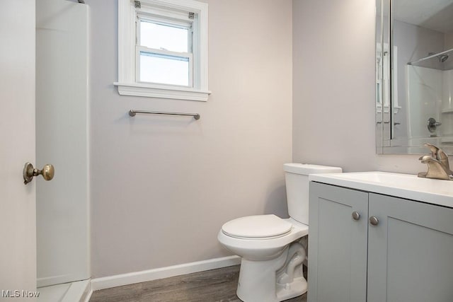 bathroom featuring toilet, vanity, walk in shower, and hardwood / wood-style flooring