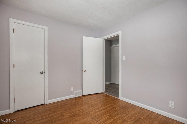 unfurnished bedroom featuring a textured ceiling and hardwood / wood-style floors