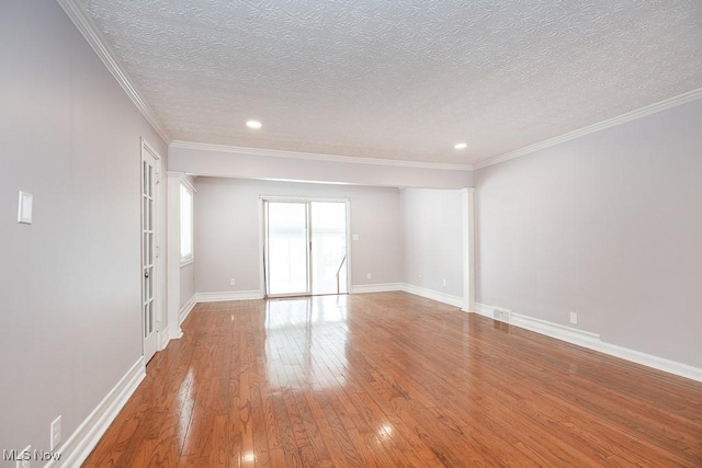 empty room featuring a textured ceiling, ornamental molding, and wood-type flooring