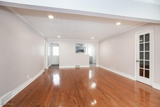 unfurnished living room with ornamental molding and hardwood / wood-style floors