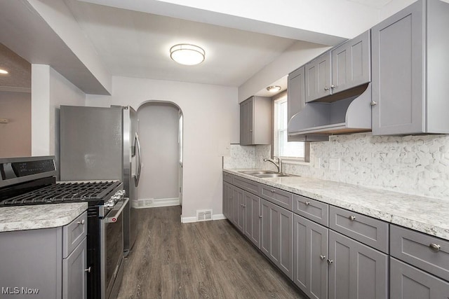 kitchen featuring dark hardwood / wood-style flooring, stainless steel gas stove, sink, backsplash, and gray cabinets