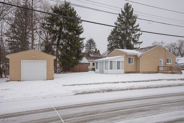 snow covered rear of property with a garage and an outdoor structure