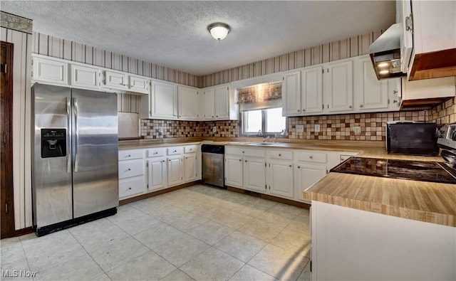 kitchen featuring exhaust hood, sink, white cabinetry, appliances with stainless steel finishes, and a textured ceiling