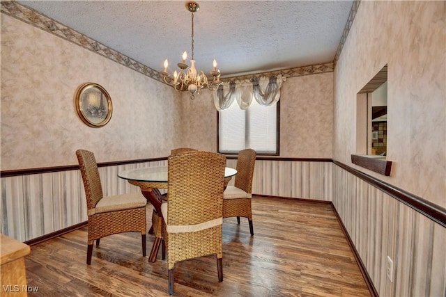 dining room featuring a textured ceiling, a chandelier, and wood-type flooring