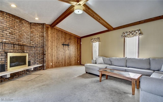 unfurnished living room featuring a brick fireplace, carpet, vaulted ceiling with beams, and wooden walls