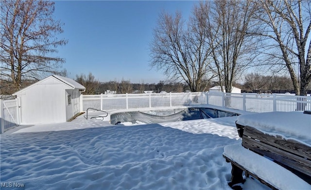 yard layered in snow with a storage unit and an empty pool