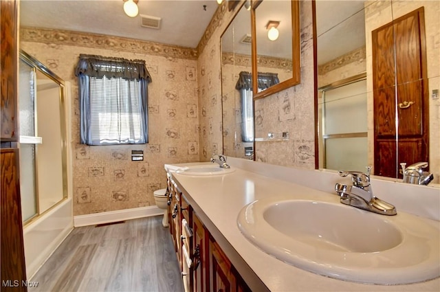 full bathroom with wood-type flooring, toilet, vanity, and combined bath / shower with glass door