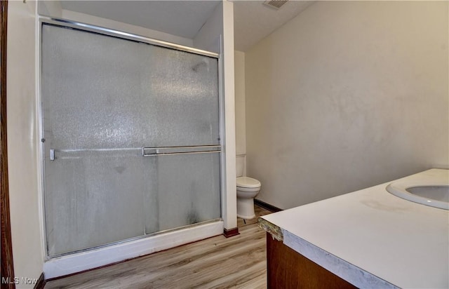 bathroom with a shower with shower door, vanity, toilet, and hardwood / wood-style flooring