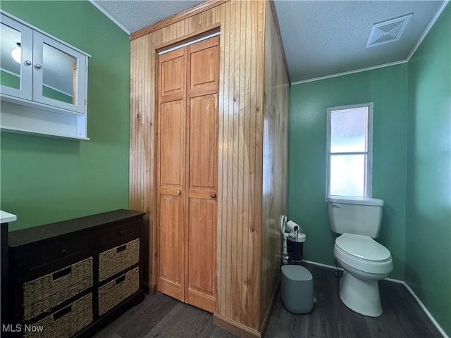 bathroom with crown molding, wood-type flooring, and toilet