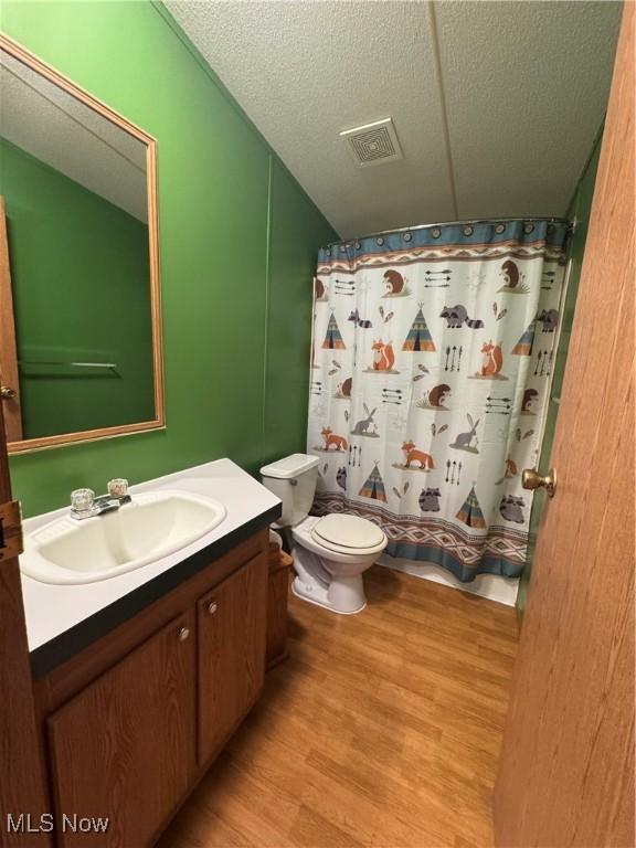 bathroom featuring toilet, a textured ceiling, vanity, curtained shower, and hardwood / wood-style floors