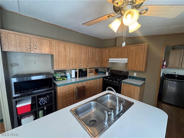 kitchen featuring washer / clothes dryer, sink, ceiling fan, a textured ceiling, and black gas range