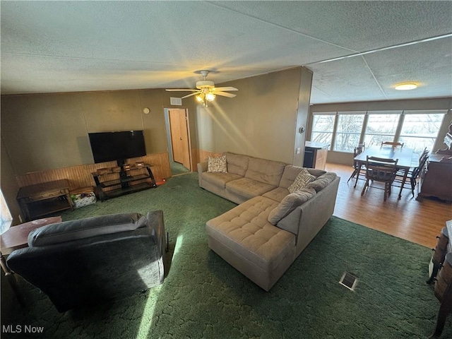 living room featuring ceiling fan, carpet floors, and a textured ceiling