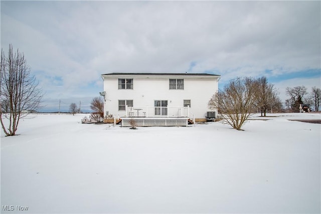 snow covered property with central AC unit and a deck