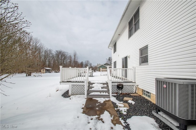 yard covered in snow with central AC unit and a deck