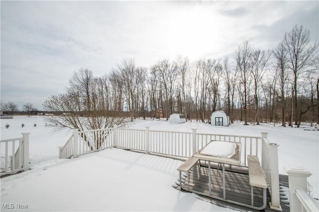 snowy yard featuring a wooden deck and a shed