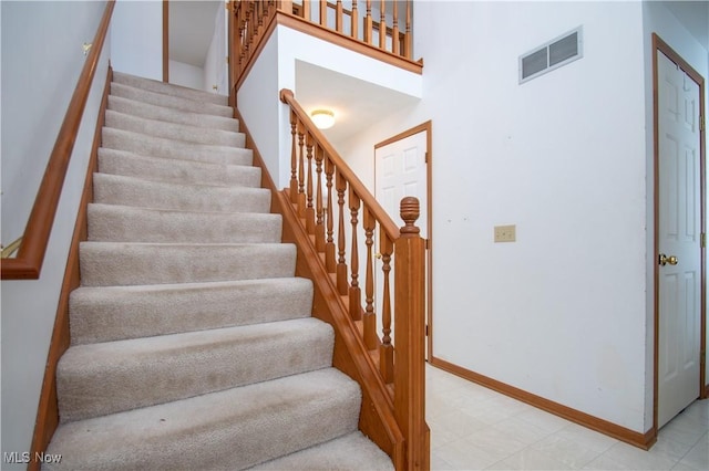 stairway featuring a towering ceiling