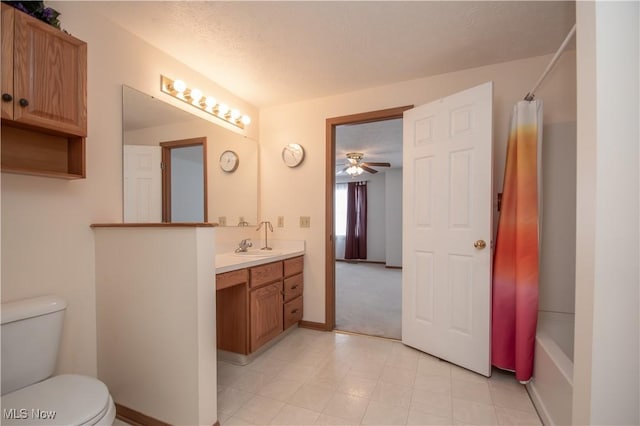 full bathroom with shower / bath combination with curtain, vanity, ceiling fan, toilet, and a textured ceiling