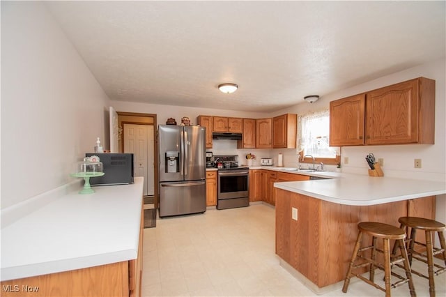 kitchen featuring stainless steel appliances, a kitchen bar, kitchen peninsula, and sink