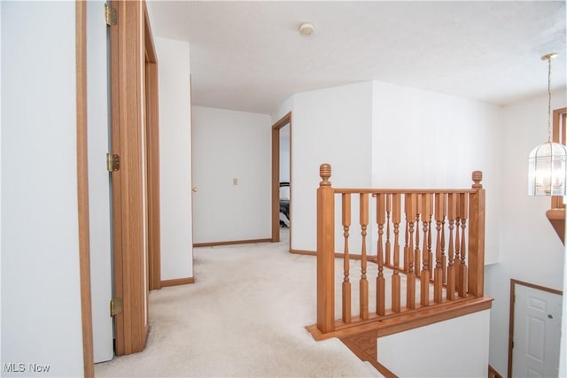 hallway with light carpet and an inviting chandelier