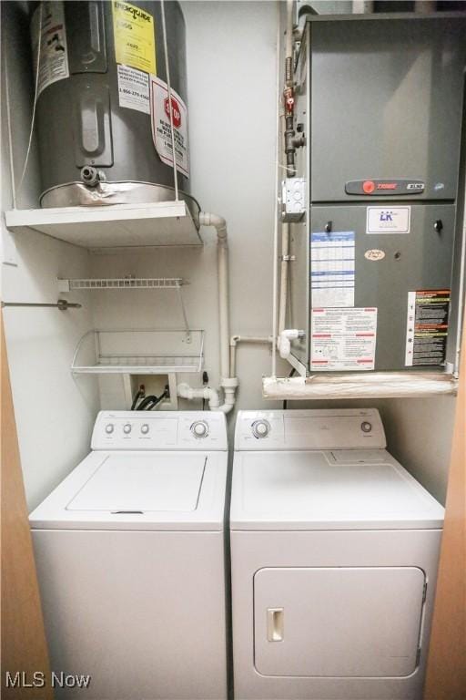 washroom featuring heating unit, electric water heater, and washer and dryer