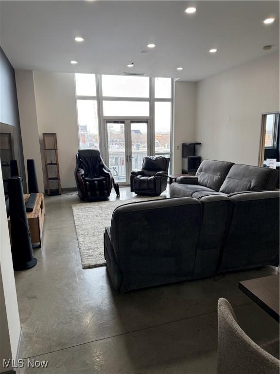 living room with french doors, floor to ceiling windows, and concrete flooring